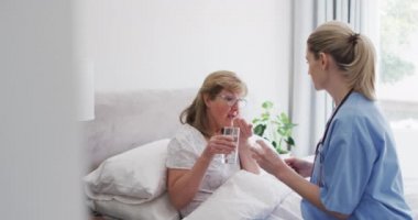 Kafkas kadın hemşire tarafından ziyaret edilen, evde kıdemli Kafkasyalı kadın, ilaç alıyor. Covid 19 Coronavirus karantinası sırasında evde tıbbi bakım, yavaş çekim.