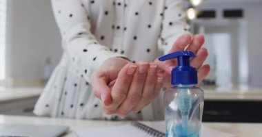 Kafkas kadınının orta kesimi ellerini yavaş çekimde mutfakta dezenfekte ederek evde zaman geçiriyor. Covid 19 Coronavirus karantina süresince sosyal mesafeler.