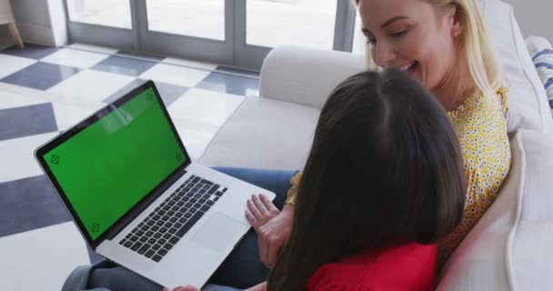 白种人女人和女儿一起呆在家里 用绿色屏幕的笔记本电脑慢吞吞地坐在沙发上 Covid期间的社会疏离 — 图库视频影像