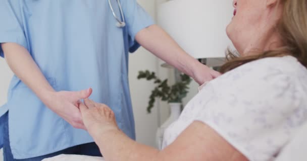 白人女性看護師が訪れた自宅のシニア白人女性は ベッドに横になって手をつないでいた Covid Coronavirus隔離中の自宅での医療 スローモーション — ストック動画