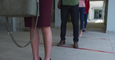 Gündelik ofiste çalışan, Covid 19 'u korumak için akıllı telefonları yavaş çekimde kullanan çok ırklı bir grup. Coronavirus Covid 19 salgını sırasında işyerinde sosyal mesafeler.