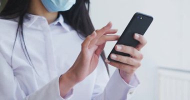 Gündelik ofiste çalışan, Covid 19 'u korumak için akıllı telefonları yavaş çekimde kullanan çok ırklı bir grup. Coronavirus Covid 19 salgını sırasında işyerinde sosyal mesafeler.