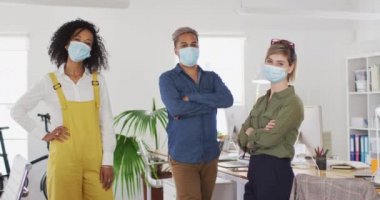 Coronavirus Covid 19 salgını sırasında iş yerinde yüz maskesi, sağlık ve hijyen takan üç kadın ve erkek yaratıcının çok ırklı portresi.