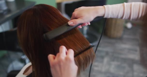 Kafkas Kadın Kuaför Kuaförde Çalışıyor Beyaz Kadın Müşterinin Saçını Düzleştiriyor — Stok video