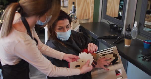 Kaukasische Friseurin Friseursalon Trägt Gesichtsmaske Zeigt Der Kaukasischen Frau Haarfärbemittel — Stockvideo