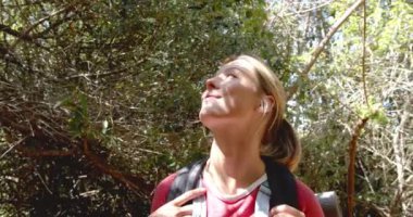 Kafkasyalı genç bir kadın güneşli bir ormanı keşfediyor, merakla yukarıya bakıyor. Günlük kırmızı bir bluz giyiyor ve bir sırt çantası taşıyor. Bu da yürüyüş ya da doğa yürüyüşü anlamına geliyor..