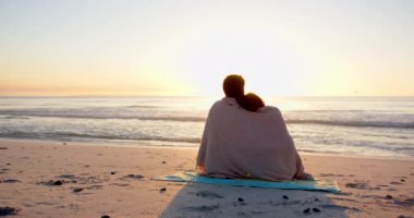 Çift ırklı bir çift, battaniyeye sarılıp sahilin batışını izlerken fotokopi çekiyorlar. Kucaklaşmaları, günün sonunda romantik bir anı akla getiriyor, ağır çekim..