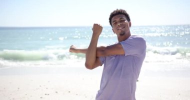 Genç, melez bir adam, fotokopi aletiyle güneşli bir plajda kollarını uzatıyor. Geniş bir şekilde gülümsüyor, deniz kenarındaki atmosferin tadını çıkarıyor. Yavaşça arka plana çarpan dalgalarla, ağır çekimde..