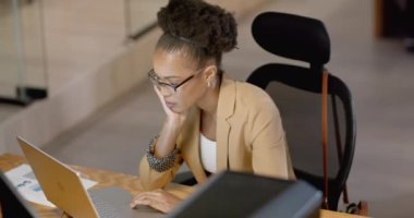 Afrikalı Amerikalı iş kadını bir ofiste dizüstü bilgisayarına odaklanıyor. Konsantrasyonu iş ortamının profesyonel doğasını yansıtıyor, ağır çekim..