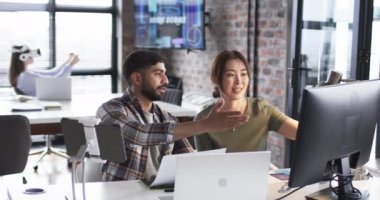 Asyalı genç bir adam ve Asyalı bir kadın teknoloji dolu bir ofiste iş konuşuyorlar. Adam sakallı ve rahat gömlekli, kadın ekranda jest yapıyor, ikisi de işine odaklanmış, ağır çekimde..