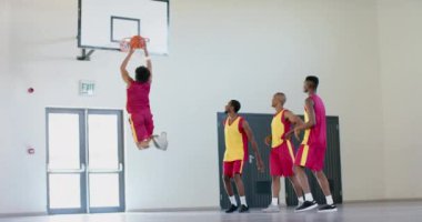 Afro-Amerikalı genç bir Afro-Amerikalının basket atışını izliyor. Kapalı alanda basketbol oynuyorlar, takım çalışması ve sportmenlik üzerine yoğunlaşıyorlar, yavaş çekim..