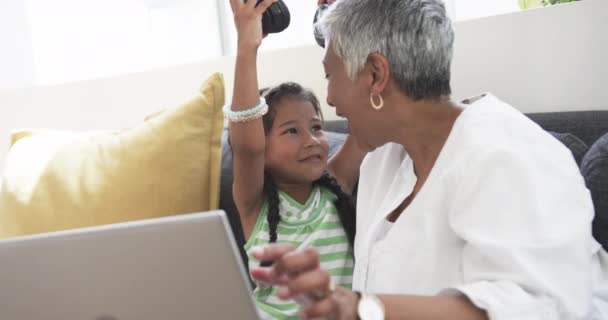 Biracial 소녀는 그녀의 할머니와 헤드폰을 환경에서 그들은 노트북에 음악이나 비디오를 — 비디오