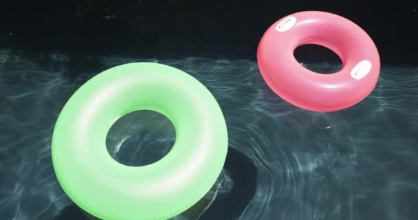 Δύο Χρωματιστά Δαχτυλίδια Κολύμβησης Επιπλέουν Στην Επιφάνεια Μιας Πισίνας Ένα — Αρχείο Βίντεο