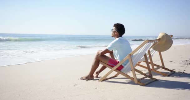 Young Biracial Man Relaxes Beach Chair Sea Copy Space Sports — Stock Video
