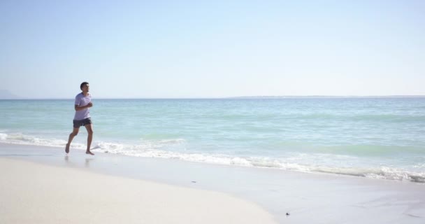 Joven Birracial Trota Largo Una Playa Soleada Con Espacio Para — Vídeo de stock