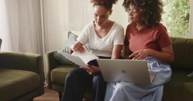 Çift cinsiyetli lezbiyen çift evdeki kanepede dokümanları gözden geçirip planlarını tartışıyorlar. LGBT, aşk, ilişki, tartışma, planlama, evrak işleri