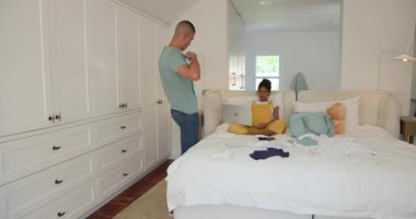 Evde çeşitli çiftler dizüstü bilgisayarlarıyla yatakta oturuyor, kıyafetleri tartışıyor ve düzenliyorlar. Yatak odası, teknoloji, giysi, ilişki, yaşam tarzı, iletişim