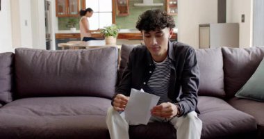 Çeşitli anne ve oğul zarfları açıyor ve gri koltukta heyecan verici haberleri paylaşıyorlar. Aile, sürpriz, neşe, iletişim, modern, yerli, bağlantı