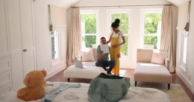 Evdeki parlak, rahat yatak odasında dizüstü bilgisayar kullanırken çeşitli çiftler evrak işlerini tartışıyor. planlama, iletişim, yaşam tarzı, işbirliği