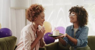 Mutlu lezbiyen çift evde renkli balonlarla gülüp el ele tutuşuyor. Mutluluk, kutlama, ilişki, aşk, neşe, birliktelik