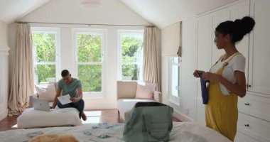 Çift ırklı çift evde bavullarını topluyor, birlikte tatile hazırlanıyorlar. Seyahat, bagaj, hazırlık, tatil, ilişki, ev hayatı