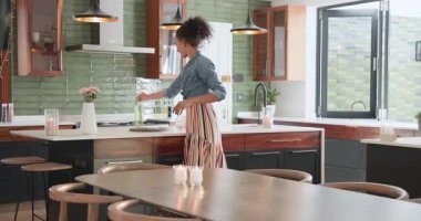 Kadın modern mutfakta neşeyle dans ediyor, müzikten hoşlanıyor ve hayatı kutluyor. Mutluluk, yaşam tarzı, enerji, hareket, ev, kutlama