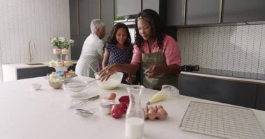 Birlikte kek pişirmek, üç nesil boyunca mutfakta kahkaha ve neşe paylaşmak. Çeşit çeşit aile, yemek pişirme, çok nesilli, birliktelik, kaynaşma