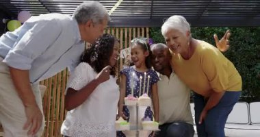 Farklı aileler doğum günlerini kutlarken genç bir kız keklerin üzerine mumlar üflüyor. Kutlama, farklı aile zamanları, doğum günü partisi, neşeli, mutlu, neşeli