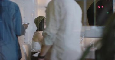 Çeşitli ekipler gece modern ofiste tablet ve laptop kullanarak proje üzerinde çalışıyorlar. Takım çalışması, işbirliği, teknoloji, dijital, işyeri, beyin fırtınası