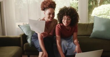 Aynı cinsiyetten lezbiyen çift evdeki parlak oturma odasındaki kanepede belgeleri gözden geçiriyorlar. LGBTQ, ortaklık, ilişki, birliktelik, bağlanma, evrak işleri