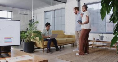 Modern ofiste iş birliği yapan genç profesyoneller dizüstü bilgisayarla projeyi tartışıyorlar. Takım çalışması, işbirliği, beyin fırtınası, yenilik, teknoloji, çalışma alanı