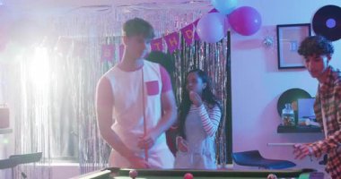 Çeşitli arkadaşlar ekose gömlekli arkadaşına doğum günü eğlencesi için bodrumda bilardo oynarken tepki veriyor. Kutlama, arkadaşlık, sosyalleşme, hareketli, gündelik, eğlence, modern