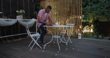 Bahçe masasında yemek hazırlayan bir adam, sıcak akşam toplantısına hazırlanıyor. Yemek, hazırlık, aşçılık, kutlama, misafirperverlik, sosyal