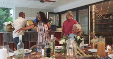 Çeşitli aileler evde kutlama yapıyor, kadeh kaldırıyor ve şenlikli yemeğin tadını çıkarıyor. Kutlama, birliktelik, yemek, tost, neşe, toplanma