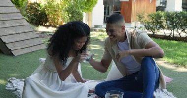 Bahçe pikniğinde eğlenen genç çift, gülümseyen kadının fotoğrafını çeken adam. fotoğrafçılık, doğa, mutluluk, aşk, rahatlık, rahatlama