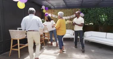 Doğum gününü kutlayan, kuşak takan gülümseyen bir kadın ve açık havada kek getiren bir adam. Kutlama, mutluluk, parti, neşe, dostluk, şenlik