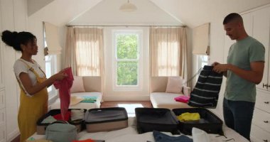 Çeşitli çiftler parlak yatak odasında bavullarını topluyor, birlikte tatile hazırlanıyorlar, evde. Seyahat, bagaj, tatil, hazırlık, kaçış, yolculuk