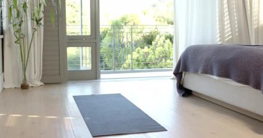 Koyu gri yoga minderi, yatak odasındaki ahşap zeminde, balkon ve bambu bitkisinin yanında. Minimalist, dinginlik, ahenk, huzur, refah, doğa esinlenilmiş, iç tasarım.