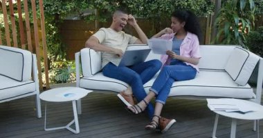 Çeşitli çiftler dizüstü bilgisayarlarla çalışıyor ve bahçe avlusunda belgeleri tartışıyorlar. Teknoloji, takım çalışması, beyin fırtınası, işbirliği, iletişim, uzaktan çalışma