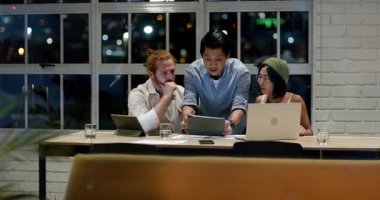 Modern ofiste, çeşitli takımlar geceleri dizüstü bilgisayarlarla projeleri tartışıyor. Takım çalışması, işbirliği, beyin fırtınası, teknoloji, iş, geç saatler