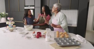 Üç nesil modern mutfakta birlikte yemek pişiriyor, neşe ve kahkaha paylaşıyor. Çeşit çeşit aile, bağlılık, birliktelik, çok nesilli mutluluk, yemek pişirme