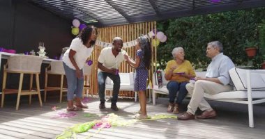 Doğumgününü dışarıda kutluyoruz, çeşitli aileler pastayı paylaşıyor ve süslemelerle gülüyor. Kutlama, mutluluk, şenlik, toplanma