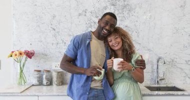 Afro-Amerikan çift seramik bardaklar ve papatyalarla mermer mutfak tezgahına gülümsüyor. Romantik, samimi, modern, iç mimari, mutlu, sevecen, yaşam tarzı