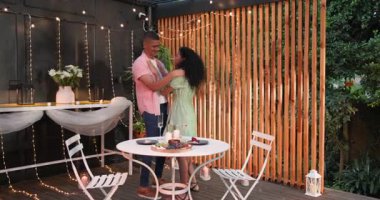 Değişik çiftler terasta birbirine sarılıyor. Tel ışıkları ve akşam yemeği için sofra hazırlıyorlar. Romantizm, mahremiyet, akşam, aşk, bahçede, kutlama