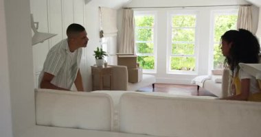 Çeşitli çiftler kutularını açıyor ve evdeki rahat oturma odasında yastıkları düzenliyorlar. Taşınma, taşınma, ev, yaşam tarzı, iç mekan, dekorasyon