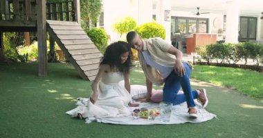 Çimenlikte piknikten hoşlanan çeşitli çiftler, kadını meyve ile besleyen erkekler, her ikisi de mutlu bir şekilde gülümsüyor. Romantik, rahatlatıcı, bahçede, mutluluk, boş zaman, ilişki