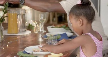 Yemek masasının etrafında toplanmak, çeşitli ailelerin evlerinde çiçekler ve mumlarla içkilerini paylaşmak. Akşam yemeği, kaynaşma, kutlama, rahat, şenlikli