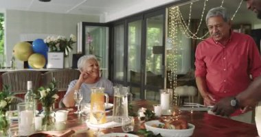 Kahkahalar ve sohbetler, çeşitli ailelerin evde, şenlik masasında birlikte yemek yemesi. Beraberlik, kutlama, yemek, kaynaşma, toplanma, tatil