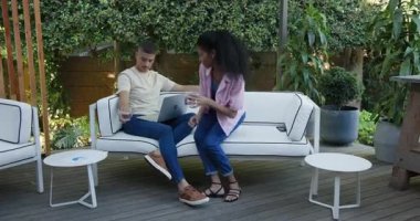 Bahçe avlusunda dizüstü bilgisayarlar ve belgeler üzerinde çalışan, odaklanmış ve işbirliği yapan bir çift. İşbirliği, takım çalışması, uzaktan çalışma, üretkenlik, iş dünyası, beyin fırtınası