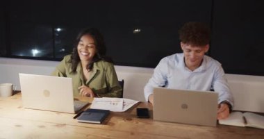 Ofiste dizüstü bilgisayarlar üzerinde çalışan kadın ve iş arkadaşı görevlere odaklanmış. İşbirliği, takım çalışması, çeşitlilik, teknoloji, bilgisayarlar, verimlilik